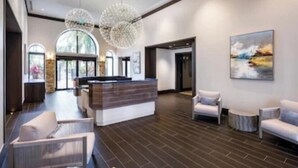 Un hall d’entrée moderne avec un comptoir d’accueil, un espace salon et de grandes fenêtres.