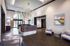 A modern lobby with a reception desk, seating area, and large windows.