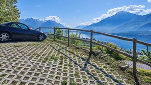 A car parked on a paved area with a wooden railing overlooking a lake and mountains. - Beautiful private villa for 6 people with WIFI, TV, terrace and pets allowed (Stazzona)