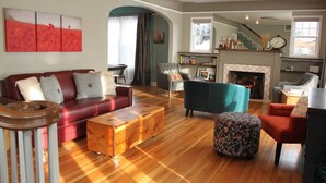 A spacious living room with a red sofa, a teal armchair, and a wooden coffee table.