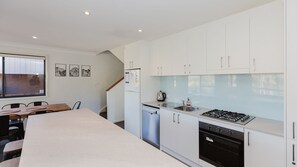 Una cocina moderna con armarios blancos, lavavajillas, estufa y pileta.