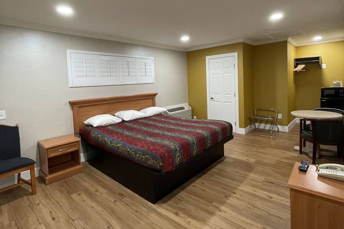 A bedroom with a bed, bedside tables, a chair, a desk, and a chair.