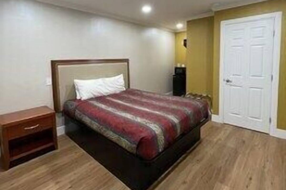 A bedroom with a bed, a nightstand, a wardrobe, and a door.