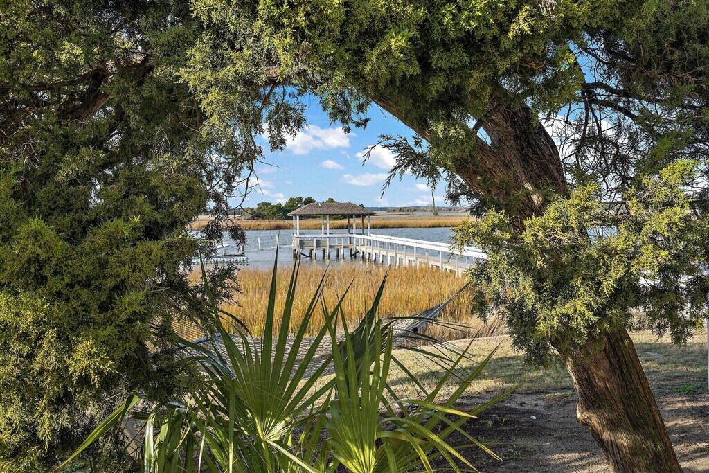 A gazebo over a dock extending into a body of water, surrounded by dense trees and vegetation.