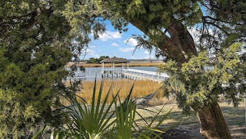A gazebo over a dock extending into a body of water, surrounded by dense trees and vegetation.