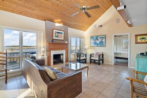 A spacious living room with a wooden ceiling, a fireplace, a sofa, and a dining area. - Pure Bliss ! Dock with Fantastic Fishing, Deep Water 24 hours, 5 min Beach! (Isle of Palms)