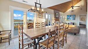 Ruime eethoek met een grote houten tafel en stoelen, een plafondventilator en uitzicht op de omgeving.