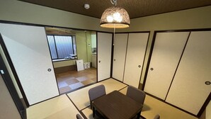 A traditional Japanese-style room with tatami flooring, a low table with four chairs, and sliding shoji screens. - Kanon House (Kyoto)