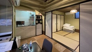 A compact room with a kitchenette, a dining area, and a sleeping area with tatami mats. - Kanon House (Kyoto)