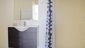 Een badkamer met een wit wastafel, donker houten wastafelmeubel, een spiegel en een douche met een decoratief gordijn.