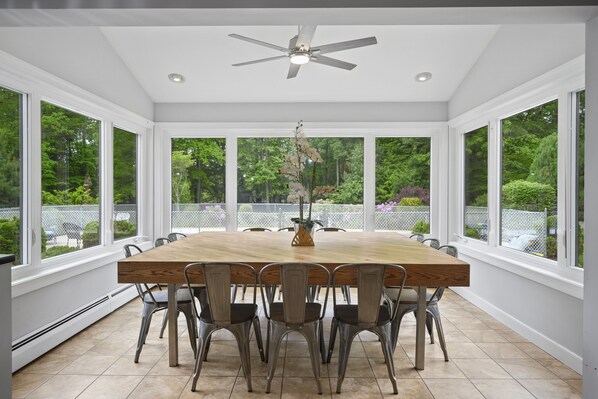 Enjoy meals in this spacious dining area with a large table and six chairs, surrounded by a serene outdoor view.