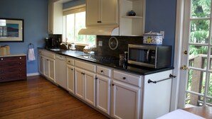 A kitchen with white cabinets, a black countertop, and a microwave. - The Tudor Rose - A classy, comfortable getaway (San Anselmo)