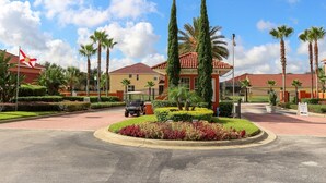 Une entrée d’hôtel bien entretenue, avec une allée pavée, des palmiers et un véhicule de transport sur le parcours de golf.