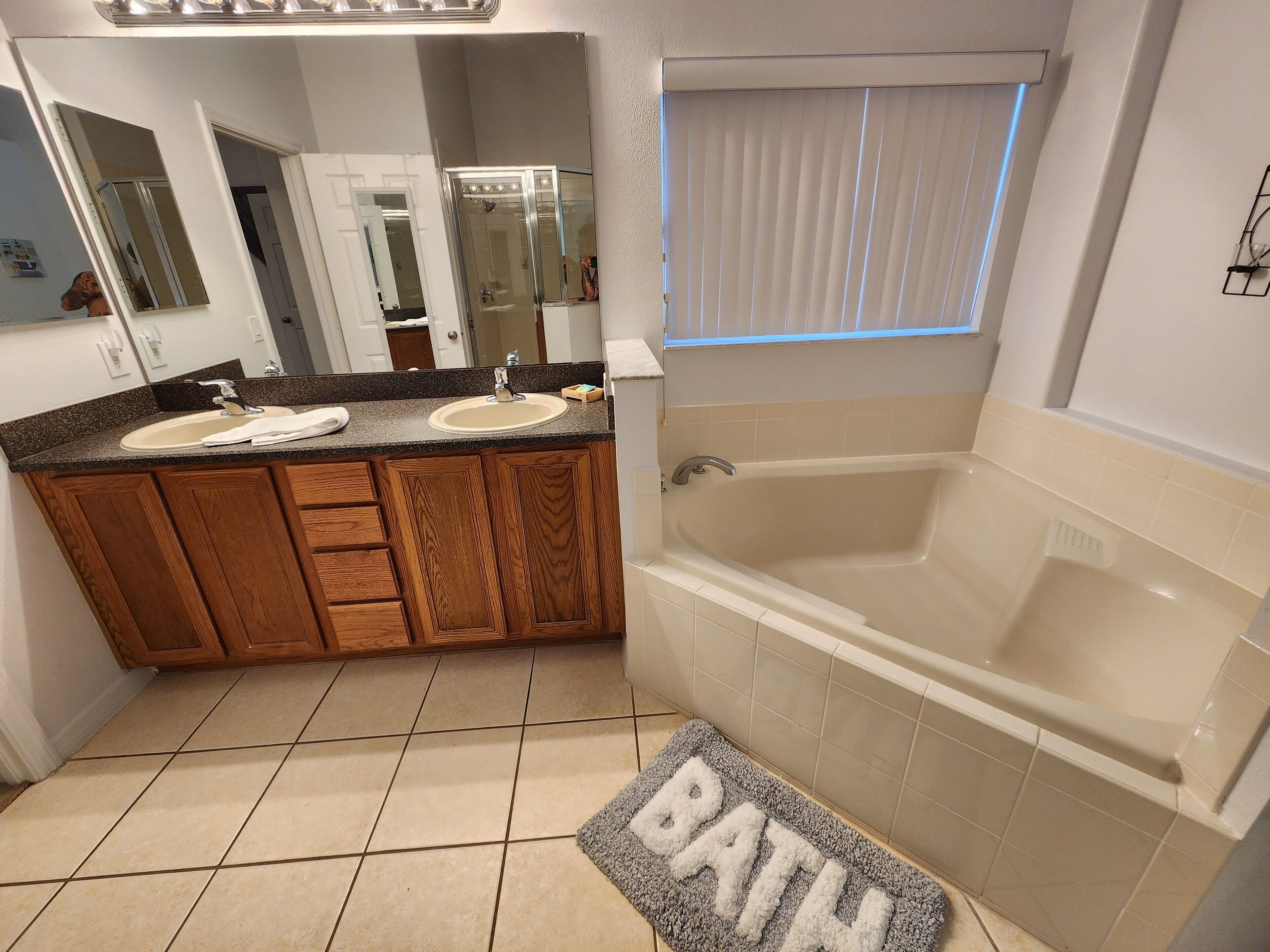 A bathroom with a double sink vanity, a bathtub, and a mirror.