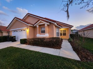 A two-story house with a garage, a well-maintained lawn, and a clear sky.