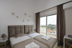 A hotel room with a large bed, a small table, a lamp, and a balcony with a view. - Piccolo Paradiso Villa A (Lachania)