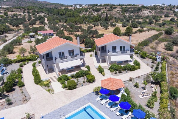 A residential area with two houses, a swimming pool, and outdoor seating. - Piccolo Paradiso Villa A (Lachania)