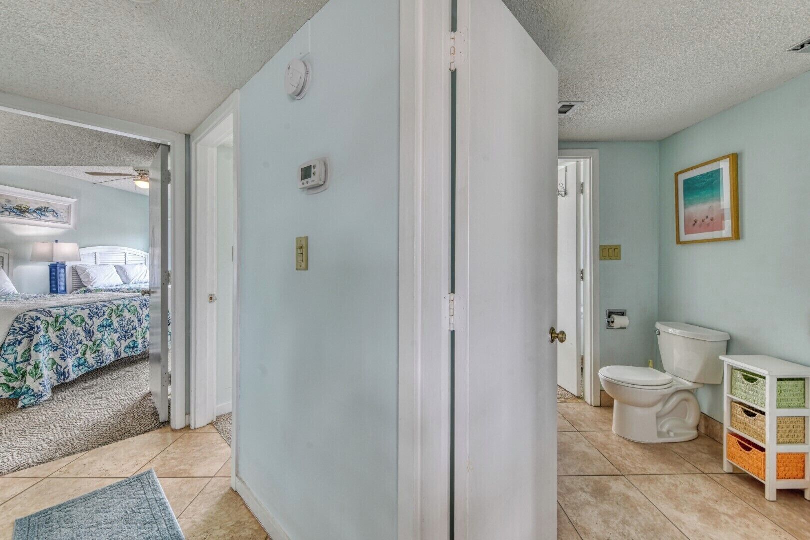 A room with a bed, a bathroom, and a door leading to another room.