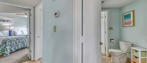 A room with a bed, a bathroom, and a door leading to another room.