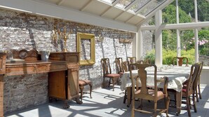 Une véranda avec un mur en briques, des meubles en bois et une table avec des chaises.