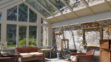 A sunlit room with a glass ceiling, stone walls, and a fireplace.