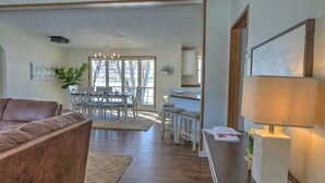A spacious living room with a brown leather couch, a dining area with a wooden table and chairs, and a kitchen area with a white cabinet and a lamp. - Alpaca My Bags & Alpaca Experience! (Silt)
