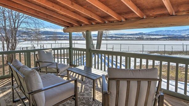 A covered outdoor seating area with a view of a river and mountains. - Alpaca My Bags & Alpaca Experience! (Silt)