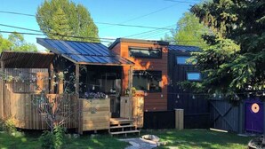 Ein modernes Haus mit einer Holzdiele, einer kleinen Veranda und einem eingezäunten Garten.