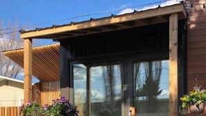 Eine Holzhütte mit Veranda, einer Holzterrasse und einem kleinen Gartenbereich mit Topfpflanzen.