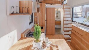 Une cuisine moderne avec des meubles en bois, un panneau indiquant qu’on y sert du café et un escalier en bois au style rustique.