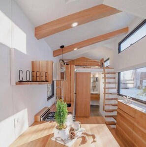 Une cuisine moderne avec des meubles en bois, un panneau indiquant qu’on y sert du café et un escalier en bois au style rustique.