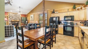 Una cocina amplia con armarios de madera, una gran mesa de comedor y una chimenea de piedra.