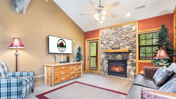 Una sala de estar acogedora con chimenea, muebles a cuadros y un televisor montado en la pared.