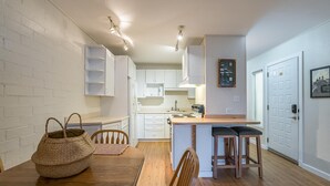 Una cocina compacta con armarios blancos, una isla de madera y una zona de comedor con mesa y sillas.