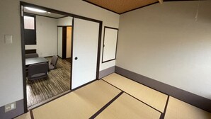 Habitació amb paviment de tatami, porta corredissa que dona a un bany i taula petita amb una cadira.
