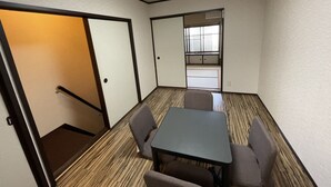 Una sala de conferències amb una taula i quatre cadires, un terra de fusta, i una porta que dona a una altra sala.