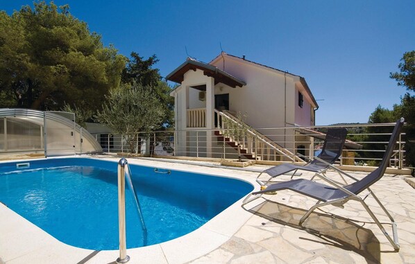 A swimming pool with a clear blue water, a covered area, and a building with a staircase. - Beautiful home in Tisno (Tisno)
