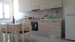 A modern kitchen with light wood cabinets, a built-in oven, and a sink.