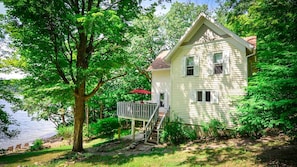 A house with a deck, a staircase, and a view of a lake.