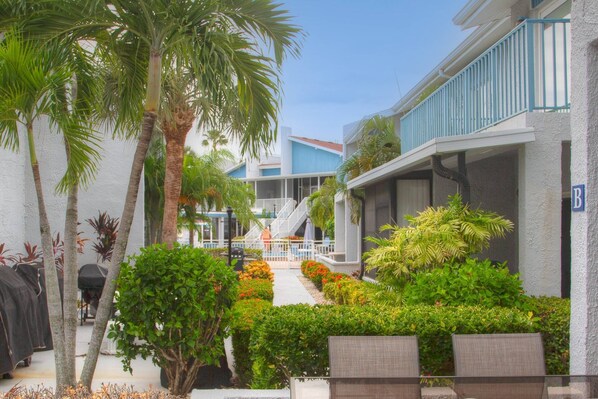 A courtyard with palm trees, a covered walkway, and a building with a blue exterior.