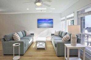 A modern living room with two grey sofas, a white coffee table, and a ceiling fan.