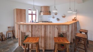 Een keuken met een houten kookeiland, hangende hanglampen en houten krukjes.