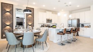 A modern kitchen with white cabinets, stainless steel appliances, and a central island with bar stools.