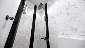 Een moderne badkamer met een douche, toilet en ligbad.