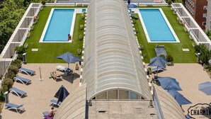 Un área de piscina en la azotea con dos piscinas rectangulares, sillones de descanso y sombrillas.