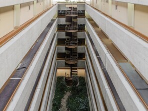 Un atrium à plusieurs niveaux, doté d’un escalier central en colimaçon, de balcons fermés et d’un petit espace jardin.