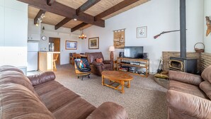 Ein gemütliches Wohnzimmer mit Kamin, Ledersofas, einem Holztisch und einem Fernseher.