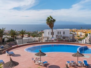A pool area with lounge chairs and umbrellas, overlooking a coastal town and the sea. - C103 big terrace, pool! (San Eugenio Alto)