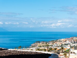 A coastal town with buildings along the shore, a clear blue sky, and the sea. - C103 big terrace, pool! (San Eugenio Alto)