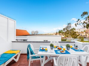 A rooftop terrace with a dining table set for breakfast, a lounge chair, and a view of the cityscape. - C103 big terrace, pool! (San Eugenio Alto)